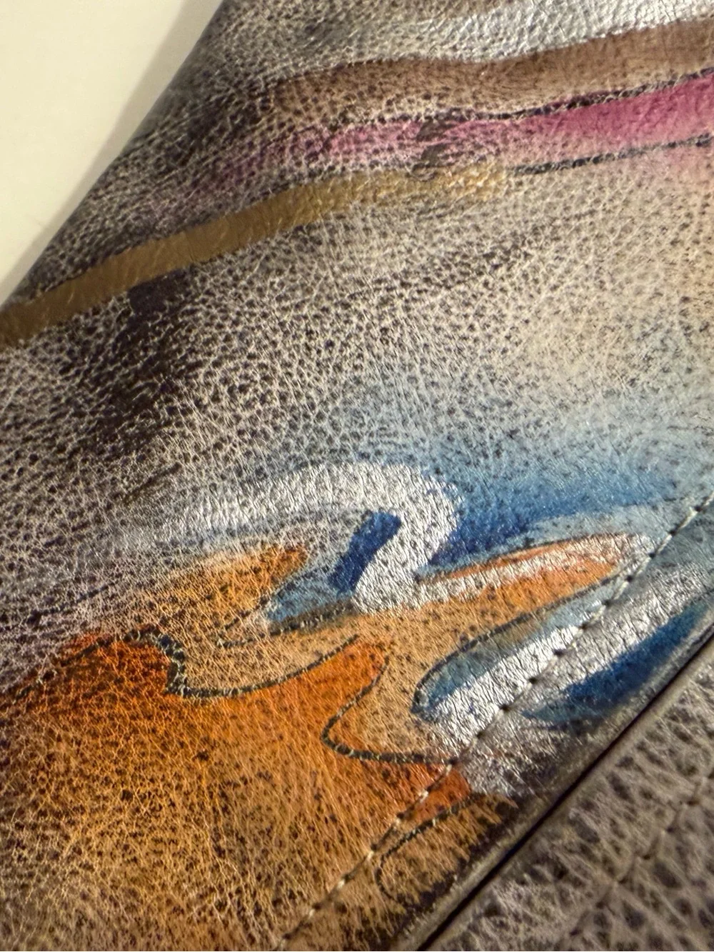 Distressed leather hobo bag with colorful abstract design on front and back.